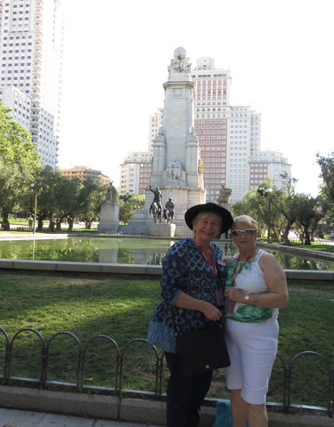 Two women in a park with large statues and water feature.