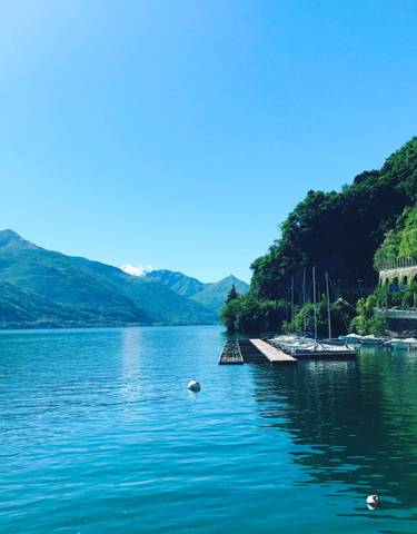 Beautiful lake with yachts and mountains in the background.