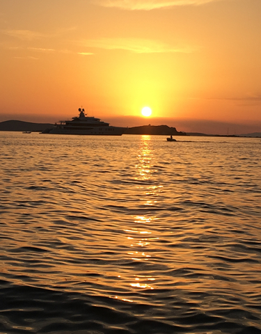 Yacht on the sea at sunset with a calm water surface.