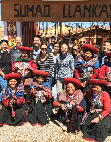 Group of people posing with locals in traditional attire.