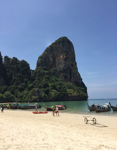 View of a dramatic cliff with boats on the sea.