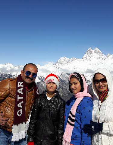 Family posing with snow-covered mountains in the background.