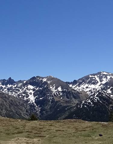 Mountainous landscape with patches of snow under a clear blue sky.