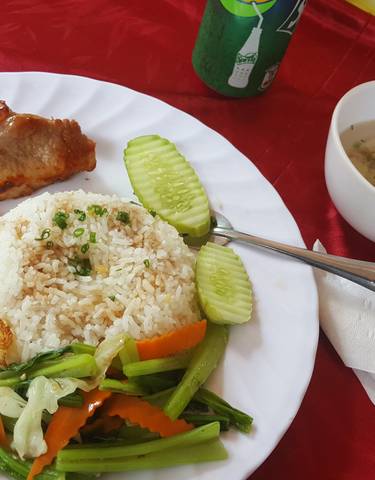 Plate of food with rice, vegetables, and meat on a red tablecloth.