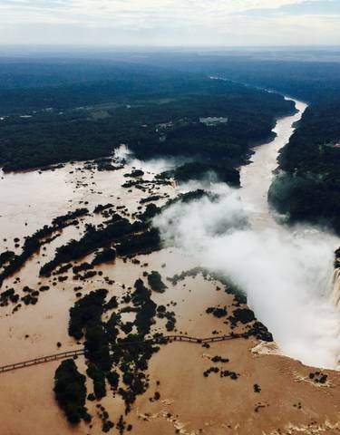 Aerial view of a river with waterfalls and surrounding forest.