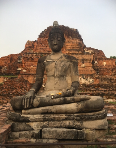 Buddha statue in front of ancient brick ruins.