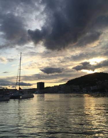 Scenic view of a harbor with boats and dramatic clouds at sunset.
