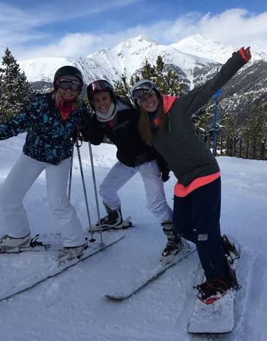 Three people posing with skis on a snowy mountain.