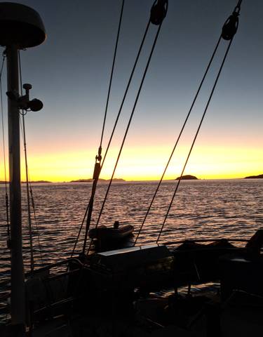 Sunset over the sea with silhouettes of a boat.
