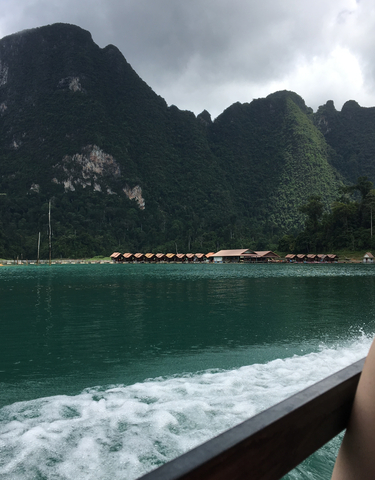 Houses on stilts on a serene lake surrounded by mountains.