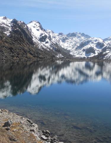 Clear lake reflecting snow-covered mountains.