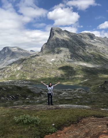 Person standing with arms raised in a mountainous landscape.