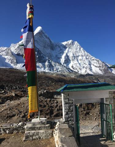 Colorful prayer flags in front of snowy mountains.