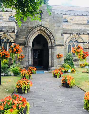 A church entrance surrounded by vibrant floral arrangements.