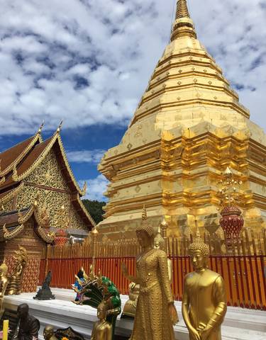Golden stupa and adorned temple with intricate carvings against a blue sky.