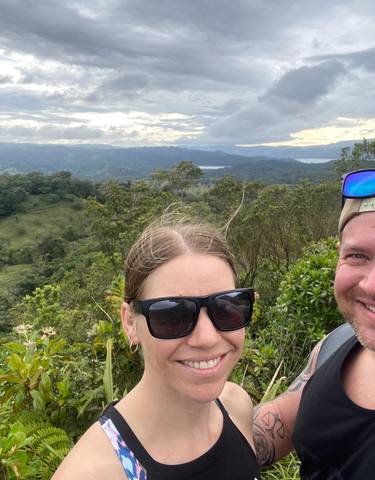 Couple posing with a panoramic view of forested hills.