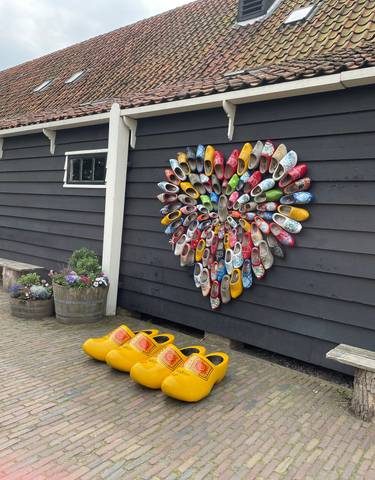 Wall with a variety of colorful wooden clogs displayed.
