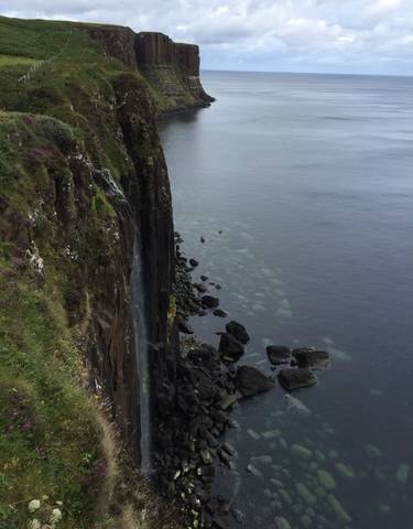 Cliffside view of a waterfall flowing into the ocean.