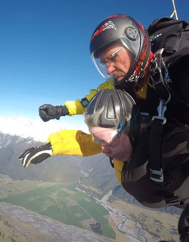 Skydivers in free fall over mountainous terrain.