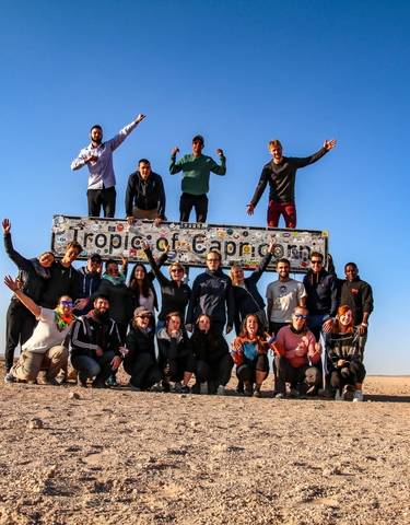 Group of people posing with a Tropic of Capricorn sign.