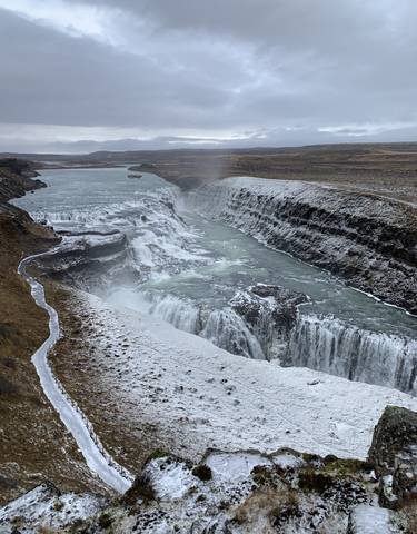 Waterfall cascading down snow-covered cliffs.
