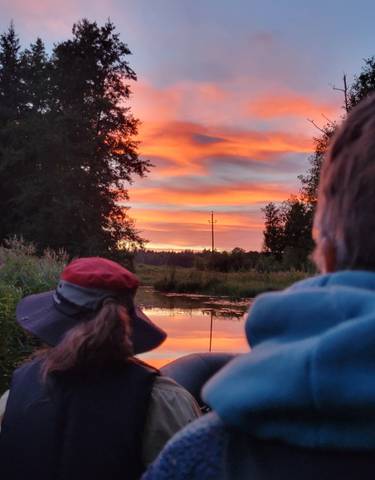 People watching a beautiful sunset over a river.