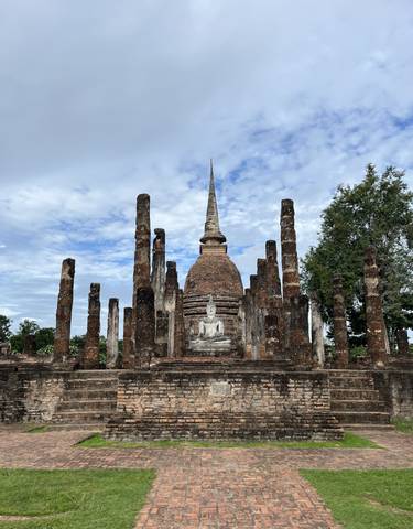 Ancient temple ruins with a spire surrounded by pillars.