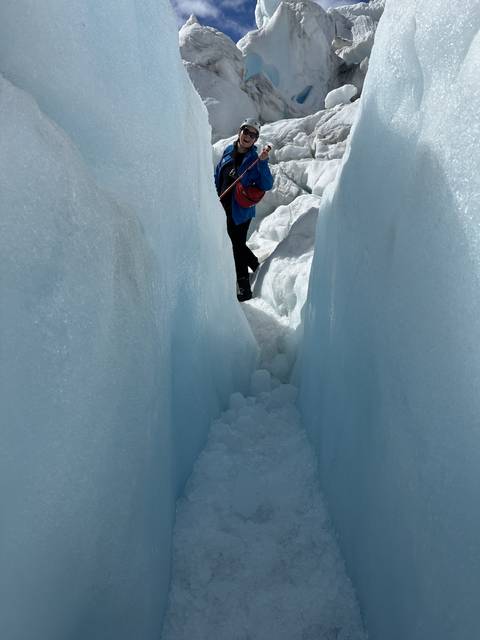 Person standing between ice walls on a glacier hike.