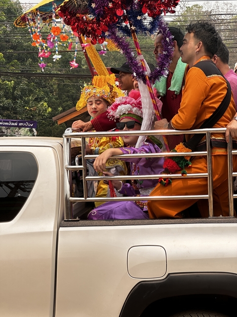 Children in traditional dress on the back of a pickup truck.