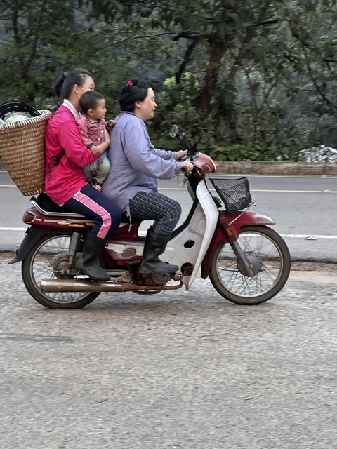 Two people on a motorbike with a basket and child.