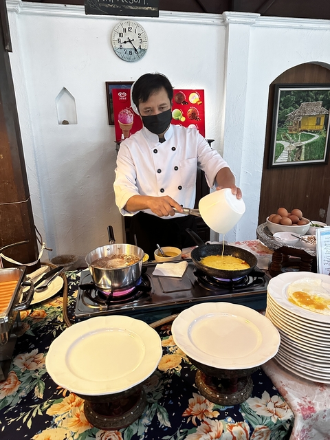 Chef preparing food at a buffet with various ingredients.