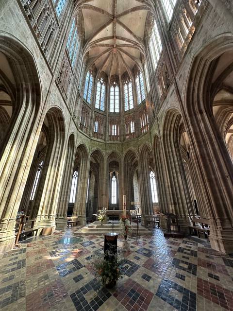 Interior of a cathedral with arches and stained windows.