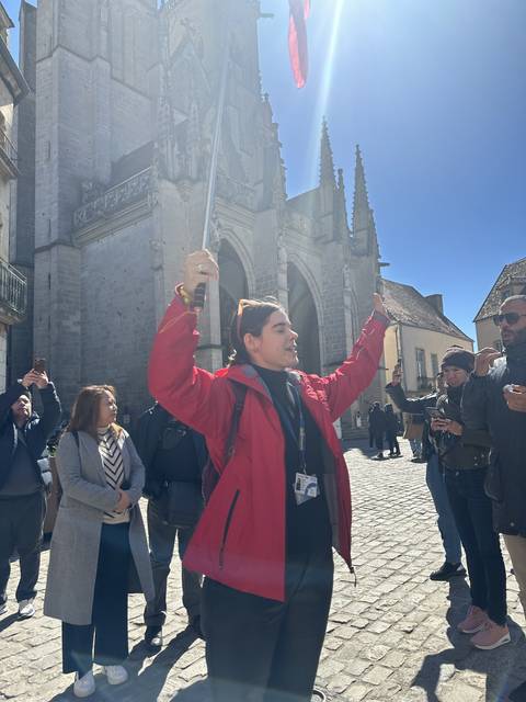 Tour guide holding a flag in a historic town.