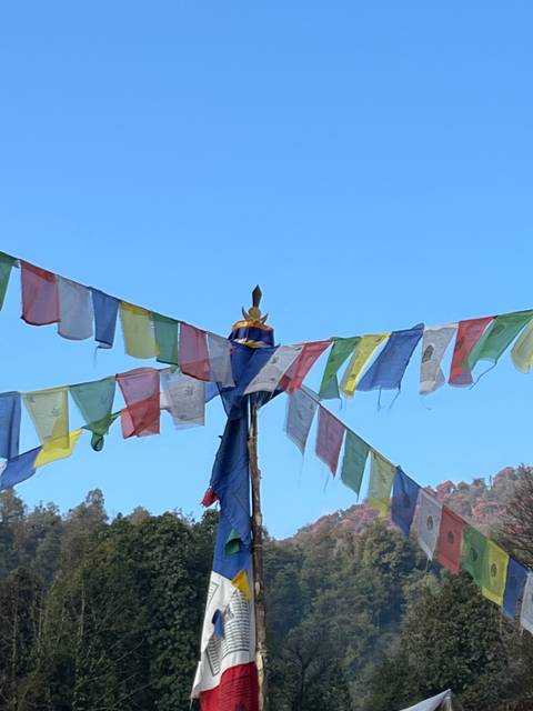 String of colorful prayer flags against a blue sky.