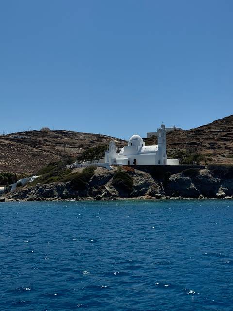 White church perched on a rocky coast with blue sea.