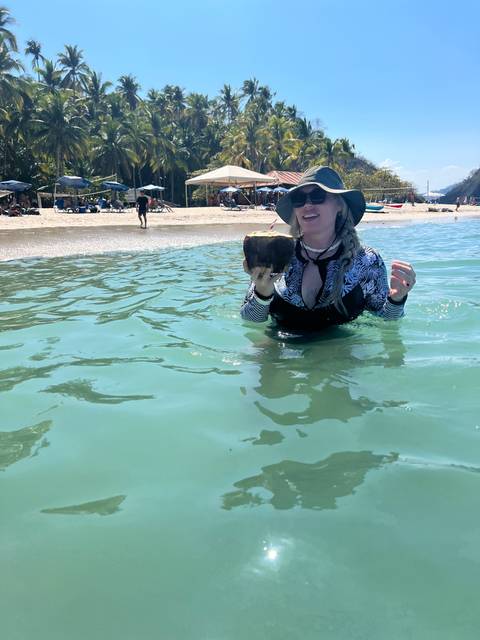 A person in a hat enjoying the water at a beach.
