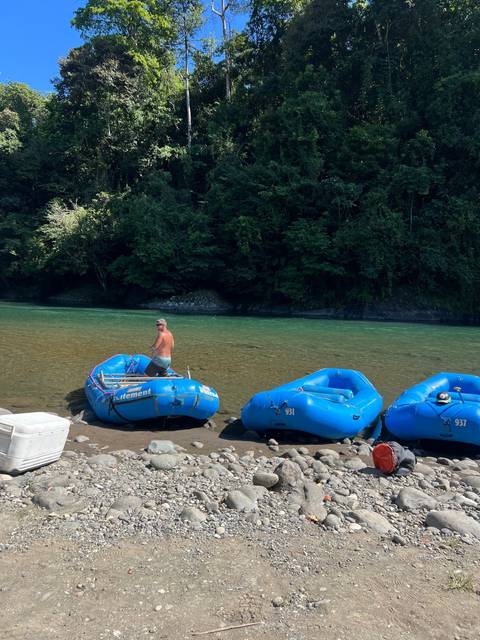A person standing with blue rafts on a rocky shore.