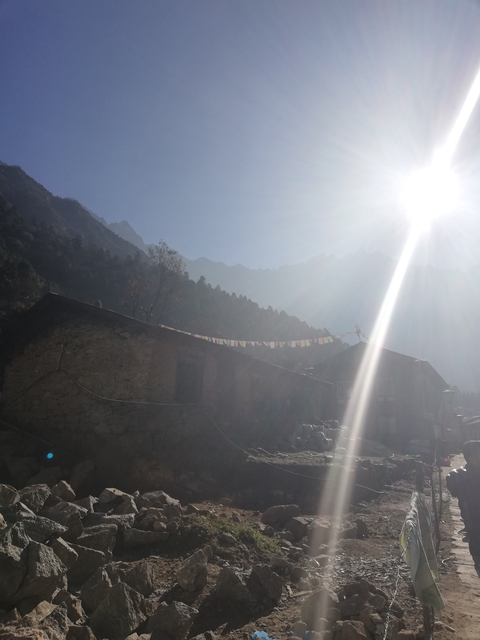 A house in the mountains with sunlight streaming dramatically into the frame.