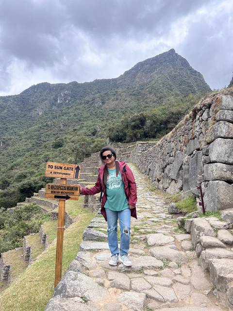 Person standing on a stone pathway, with mountainous landscape behind.