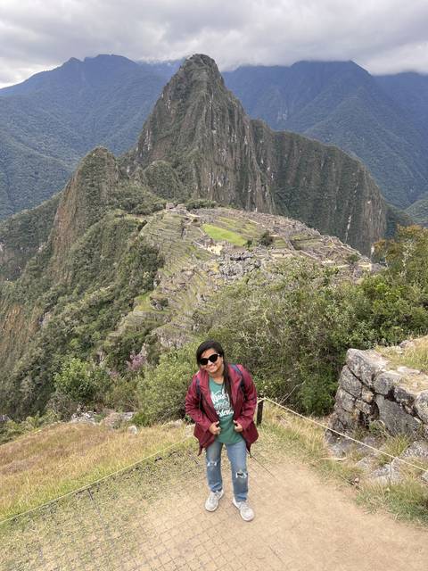 Person posing with a view of Machu Picchu in the distance.