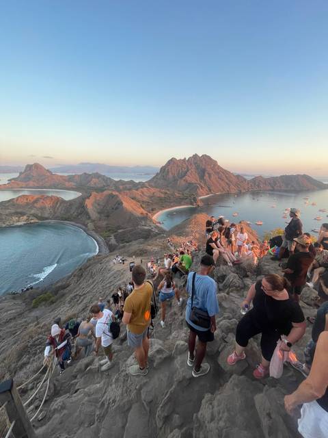 Crowd on a rocky cliff with scenic background.