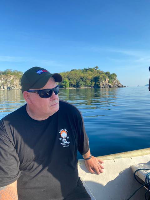 Person sitting on a boat with calm waters and small islands.