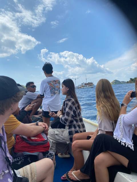 Passengers on a boat, some sitting and looking out at the water.