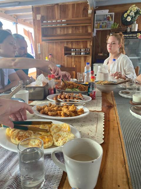 People having breakfast with a variety of dishes inside a boat cabin.