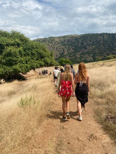 People walking on a dirt path surrounded by grasslands.