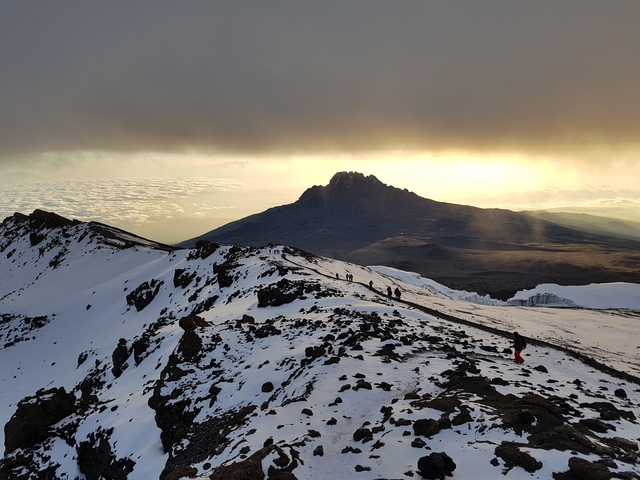 People hiking along a snowy mountain ridge.