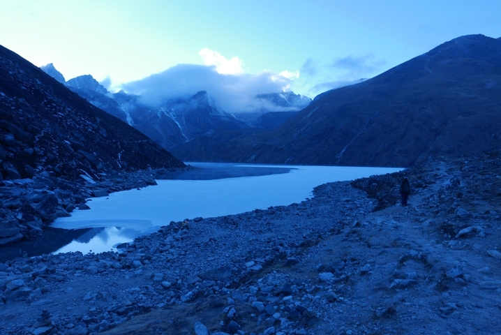 Frozen lake in a mountainous terrain with clouds.