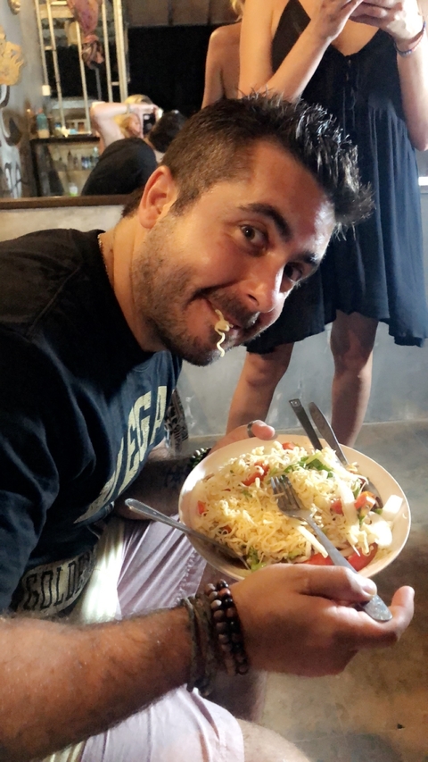 Person eating noodles from a plate indoors.