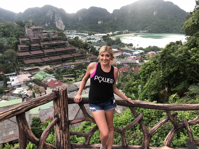 Woman posing on a scenic viewpoint overlooking a coastal town.