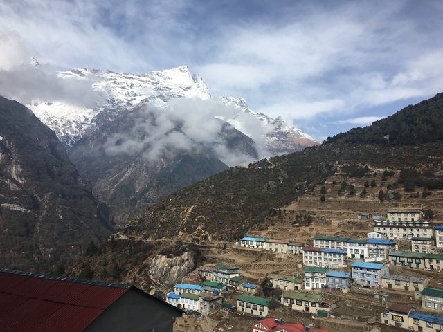 Hillside village beneath snow-capped mountains.